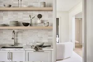 A minimalist kitchen with white subway tiles, marble countertops, and wooden shelves.