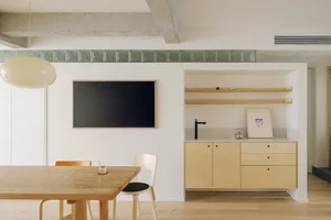 Modern minimalist kitchen featuring wooden furniture and concrete accents.
