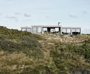 簡約住宅外觀，呈現現代低矮建築，搭配大面窗與木質外牆。