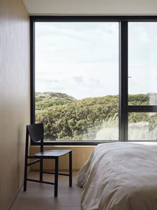 A minimalist bedroom with a large window overlooking greenery.