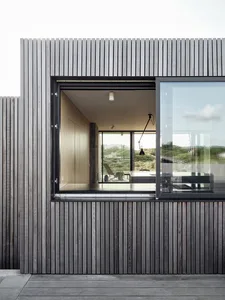 Modern exterior wall of a house with wooden slats and sliding glass doors.