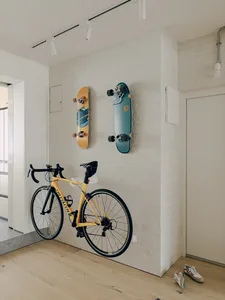 A minimalist modern interior featuring a brick wall display of two skateboards and a bicycle hanging on the wall.