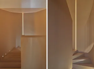 Modern interior design featuring wooden stairs and linear lighting in a sleek, contemporary setting.