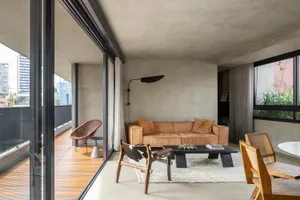 A modern living room with a concrete ceiling, brown leather sofa, and wooden accents.