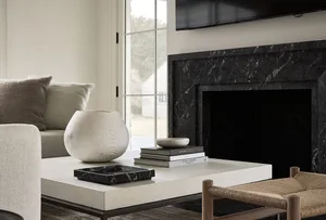 A modern living room featuring a marble fireplace, coffee table, and seating area.
