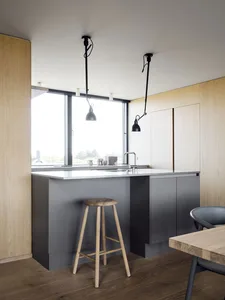 A modern minimalist kitchen with concrete countertops and wooden stools