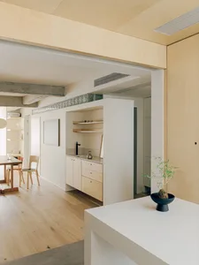 Modern minimalist kitchen with white cabinets, wooden flooring, and a minimalist design aesthetic.