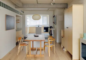 A modern minimalist kitchen with wooden furniture, glass cabinets, and concrete countertops.
