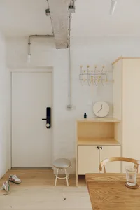 A minimalist living room with white walls, wooden furniture, and metal accents.