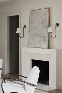 A minimalist living room with a concrete fireplace, abstract artwork, and white furniture.