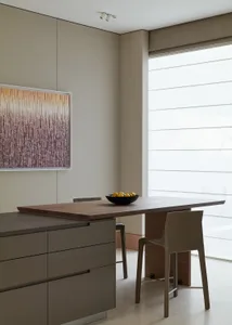 Modern, minimalist kitchen featuring wood cabinets and a wooden dining table with a bowl of oranges.