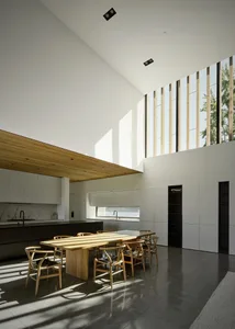 Modern kitchen with minimalist design featuring wood dining table, marble counter, and concrete flooring.