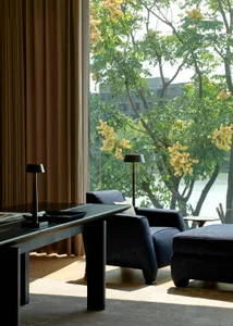 A well-designed modern fashion interior featuring a textured cloth fabric living room with a view of greenery outside.