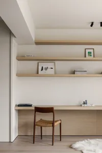 A modern home office with wooden shelves and a woven chair.