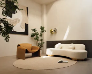 A modern living room with a circular sofa, potted plants, and abstract wall art.