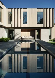A modern architectural design featuring a wooden exterior reflected in a calm water body.