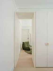 A minimalist living room with wood flooring and a green lounge chair.
