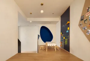 A minimalist playroom with hardwood floors, a blue egg-shaped chair, and a chalkboard wall.