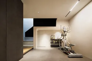 A sleek, modern home gym area with concrete walls, metal accents, and an elliptical trainer.