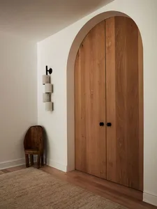 A modern interior featuring an arched doorway with wooden door.