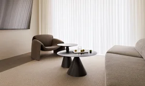 A modern living room with textured fabric furniture, a coffee table with a book and decorative objects, and a large window wi