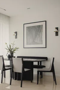A modern minimalist dining room featuring a wooden table, chairs, and a bench, with a wall-mounted black and white photograph