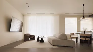 A modern minimalist living room with neutral materials and a large window.