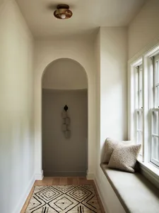 A cozy window seat with neutral-toned cushions and a textured rug, featuring a minimalist and inviting interior design.