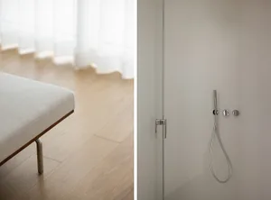 A minimalist bathroom showcasing a glass shower handle mounted on a white wall.