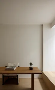 Minimalist home office with wooden desk and chair, minimalist decor, and white walls.