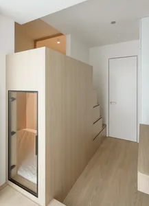 A minimalist interior design featuring a white door, wooden walls, and a glass panel.