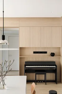 A minimalist music room with wooden walls, featuring a black piano and a shelf with a small black object.