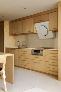 A modern, minimalist kitchen with wooden cabinets and drawers, white countertops, and a sleek, clean design.