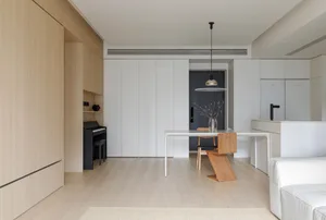 Modern apartment kitchen with white cabinets, wooden floor, and white rug.