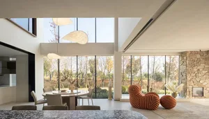 Modern living room with concrete floor and large glass windows showcasing a view of trees.