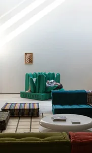 A modern interior design featuring a teal sofa with a concrete floor and high ceiling.