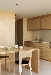 Modern kitchen interior with wooden countertops, cabinets, and table, featuring sleek design and clean lines.