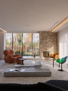 A modern living room featuring a clay brick wall, large windows, and comfortable seating.
