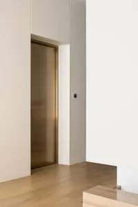 A modern lobby with a glass elevator, minimalist design, and sleek finishes.