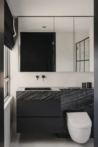Modern minimalist bathroom featuring black and white marble tiles and a black vanity with a sink.