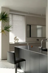 A modern minimalist kitchen with sleek, grey cabinets and a concrete countertop.