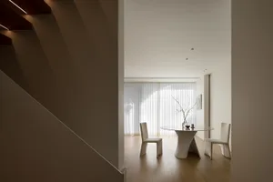 An elegant minimalist residential interior featuring wood flooring, glass walls, and sleek metal accents.