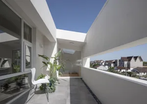 極簡建築清水模陽台區，擺放白色單椅與盆栽植物，眺望住宅景觀