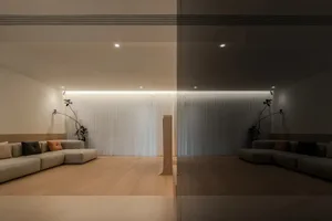 Interior design featuring a modern minimalist living room with light wooden flooring, a sleek glass partition, and a comforta