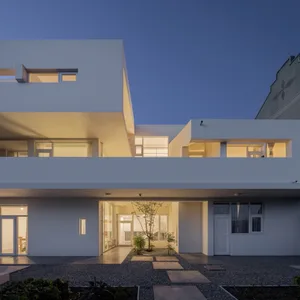 Modern residential building with concrete exterior and illuminated windows during dusk.