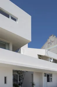 White modern building with sleek concrete balconies against a clear blue sky.