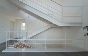 Metallic staircase in an interior space with white railings and wooden steps.