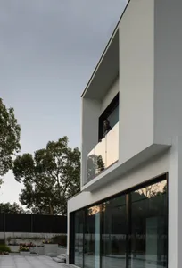 Modern exterior of a house featuring white stucco siding and glass doors.