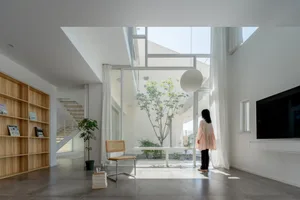 A minimalist living room with concrete flooring, large glass windows, and white furnishings.
