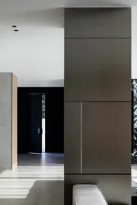 A minimalist, modern interior space with concrete walls, dark accents, and natural light coming through a window with a view 